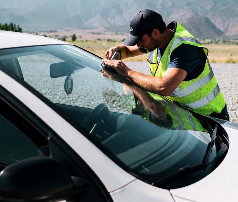 auto glass technician replacing a windshield at a roadside stop
